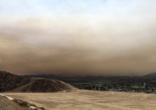 Heavy smoke from a wildfire is seen from Golden Valley Road and Five Knolls Drive Santa Clarita, Calif., on Saturday, July 22, 2016. The fire in northern Los Angeles County grew, darkening skies with smoke that spread across the city and suburbs, reducing the sun to an orange disk at times. The South Coast Air Quality Management District warned that at times air would reach unhealthy levels. The fire erupted Friday afternoon in the Sand Canyon area near State Route 14 as the region was gripped by high heat and very low humidity. (Katharine Lotze/The Santa Clarita Valley Signal via AP)